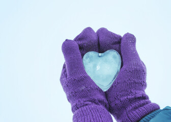 Female hands in knitted mittens with heart of snow in winter day. Love concept. Valentine day background.