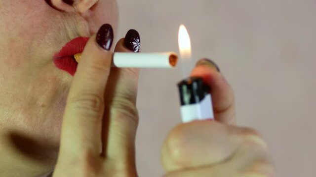 Close-up portrait of a Caucasian woman over 40 lighting a cigarette from the fire of a lighter. bad habits in women. Woman lips with a cigarette. macro. selective focus