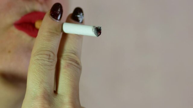 Close-up of lips of a middle aged Caucasian woman lighting a cigarette with a filter lighter. A blonde 40-45 years old smokes a cigarette and enjoys. Bad habit in women. Selective focus