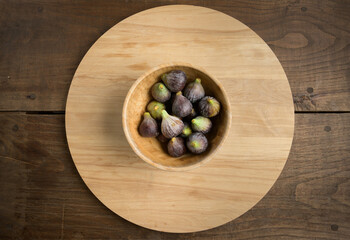 Top view figs in wooden bowl on wooden table, with copy space. High quality photo