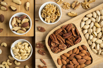 Different nuts and bowls closeup on a wooden table and brown background. Peanut, nut, cashew, almond, hazelnut, pistachio