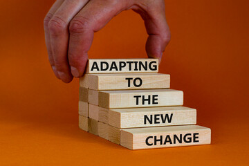 Adapting to the new change symbol. Wooden blocks with words Adapting to the new change on orange...