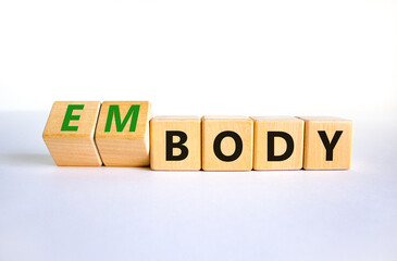 Body and embody symbol. Turned wooden cubes and changed the concept word body to embody. Beautiful white table, white background, copy space. Medical, body and embody concept.