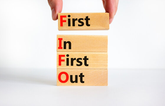 FIFO first in first out symbol. Concept words FIFO first in first out on wooden blocks. Beautiful white table, white background. Businessman hand. Business FIFO first in and out concept. Copy space.