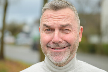 Middle-aged man winking at camera with a cheesy grin