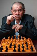 Portrait of professional chess player, posing with board staring at camera. Classical formal suit, vintage look. Competitive strategy game.