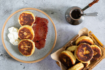 fried cottage cheese pancakes and jezve on light concrete background top view