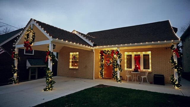 Christmas lights turn on in the early evening on a typical Pennsylvania modest yellow brick home. Pittsburgh suburbs.  	
