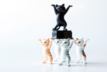 Toy kittens are dancing with a black coffin. Concept of a funeral procession dancing with a coffin. White background. Stay at home or dance with us. Call for self-isolation during a pandemic