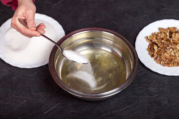 Mixing raw egg whites in a bowl with added sugar