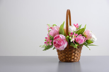 Beautiful bouquet of pink peonies. Floral composition in straw basket on light gray background