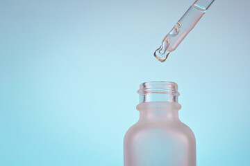 face serum oil drop with dropper glass bottle pipette on blue background close up