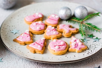Christmas cookies with pink icing in a plate on the table. Festive treat. Close-up