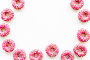 Frame of pink glazed donutes with sprinkles, top view