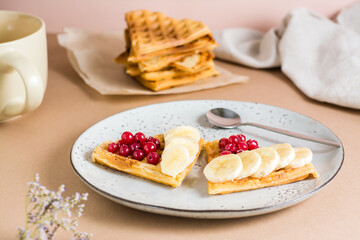 Heart shaped Belgian waffles with red berries and banana on a plate on the table. Valentine's Day. Close-up