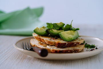 Sliced avocado on toasted bread on plate served with cilantro