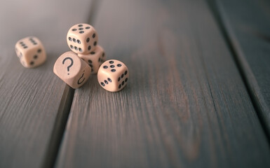 Concept photo of some game dice with question mark on wooden background