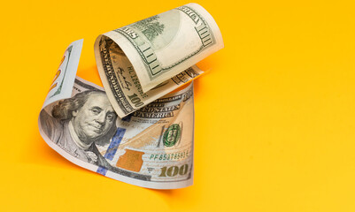 One hundred dollar bills closeup on yellow background