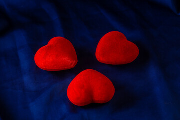 Three red hearts lie on a dark blue background, top view. Love triangle concept. Family concept of three.