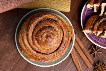 Cinnamon roll sweet pastry with spices on the table top view stock images. Delicious fresh cinnamon bun on a plate still life above stock photo