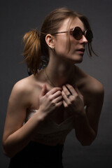 Studio portrait of a young woman in sunglasses, on a black background