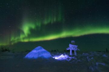Northern Lights with an igloo and snow inukshuk in the foreground