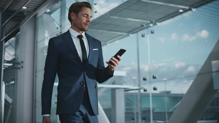 Airport Terminal: Businessman Walks to His Flight Gates, Uses Smartphone, Doing e-Business, Browsing the Internet with App. Digital Entrepreneur Remote Work Online While Traveling Through Airline Hub - Powered by Adobe
