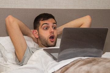 surprised man with computer in bed