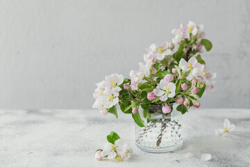 Branches with white apple flowers in a transparent glass