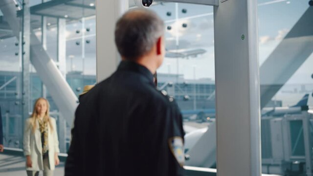 Airport Terminal: Security Officer Checks and Separates Diverse Group of People Walking Through Metal Detector Scanner Gates for Plane Flight Boarding. Crowd of Travelers Going on Vacation Trips