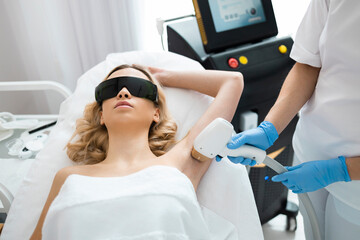 Beautiful girl on a laser hair removal procedure armpits in cosmetology salon. Smooth and silky skin concept