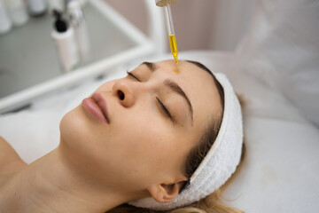 Beautiful blonde woman getting professional face treatment with nourishing oil. Facial massage....