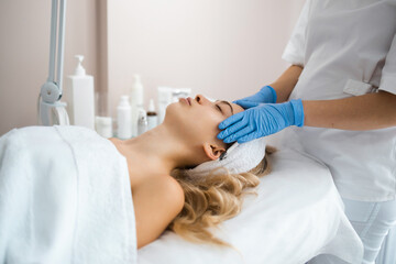 Obraz premium Beautician massaging the face of young girl in latex gloves. Masseur doing relax facial massage at spa salon