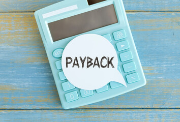 PAYBACK text on sticker with calculator on wooden background