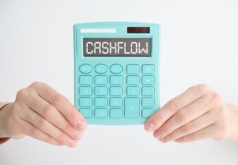 On a wooden table there is a black pen and a calculator with the text CASHFLOW.