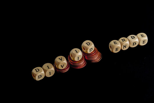 Staples of coins with wooden letters cubes forming the word "Divid Ende" in german language, concept picture for the end of dividend.