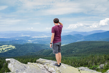 Man traveler feeling free enjoying view of mountains.Male standing on rock after climbing.Adventure,sport,activity,wanderlust freedom travel concept.Solo man on summit.Succsseful tourist relaxing