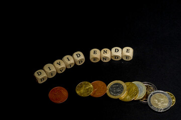 Several euro coins with wooden letters cubes forming the word "Divid Ende" in german language, concept picture for the end of dividend.