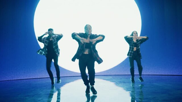Diverse Group of Three Professional Dancers Performing a Hip Hop Dance Routine in Front of a Big Led Wall Screen with VFX Animation During a Virtual Production in Studio Environment. 105 BPM Song.