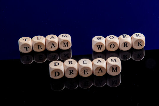 White letter cubes forming the three words Team, Work, Dream in front of mirroring background, concept picture teamwork