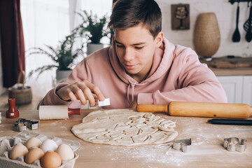 Valentine's Day cooking teenage boy makes cookies in the shape of hearts, romantic Valentine's Day...