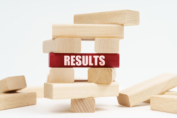 On the white surface there is a ruined tower made of planks, on a red plaque there is an inscription - RESULTS