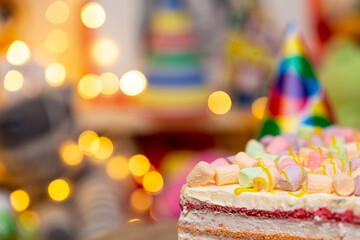 Concept of holiday or birthday. Multicolor five layer cake with colored marshmallow on the top and defocused lights as background