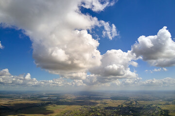 Aerial view from high altitude of earth covered with white puffy cumulus clouds on sunny day