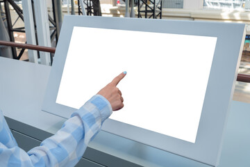 Woman hand touching blank interactive touchscreen white display of electronic kiosk at futuristic exhibition or museum: close up. White screen, mock up, copyspace, template, technology concept.