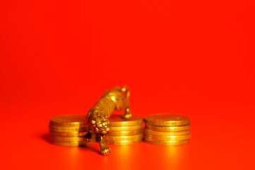 Metal tiger with coins on a red background. Financial symbol. Close-up subjects.