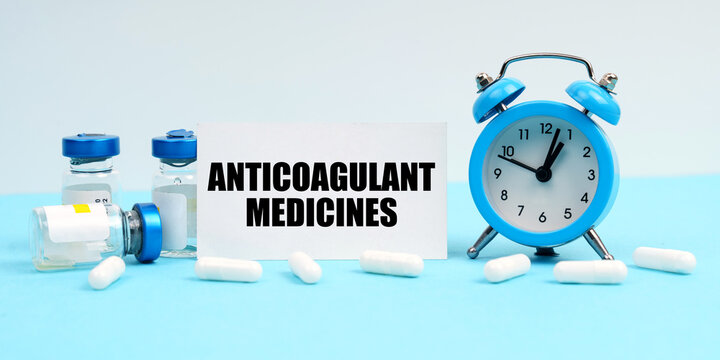 An alarm clock, pills, injections and a card with the inscription - Anticoagulant Medicines