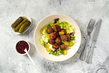 Swedish meatballs with salad, pickled cucumber and lingonberry jam in a bowl. A traditional...