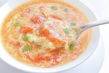 Tomato egg drop soup in a white bowl.  Traditional Chinese food.