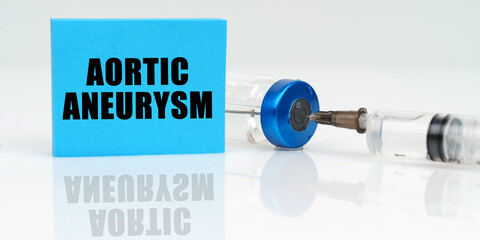 On a white reflective surface are a syringe, an injection and a blue plaque that says - Aortic...